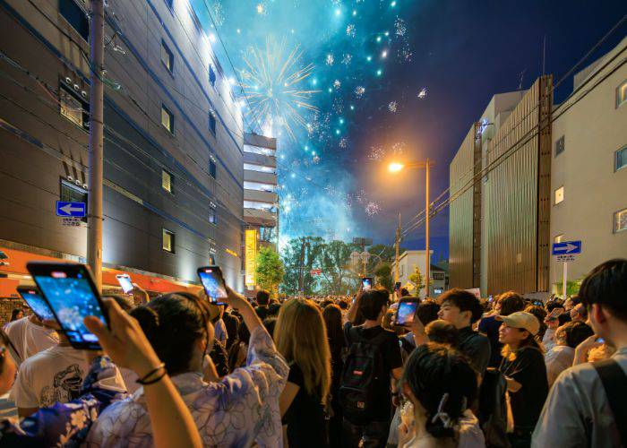 Crowds line the streets of Osaka, attempting to get a glimpse of the fireworks at the Osaka Tenjin Fireworks Festival.